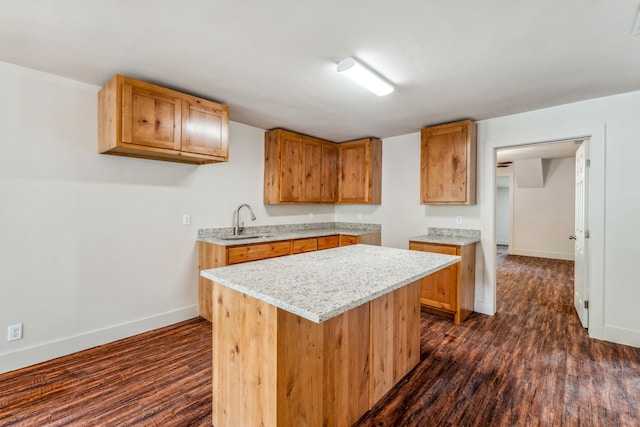 kitchen featuring sink, light stone counters, dark hardwood / wood-style flooring, and a kitchen island