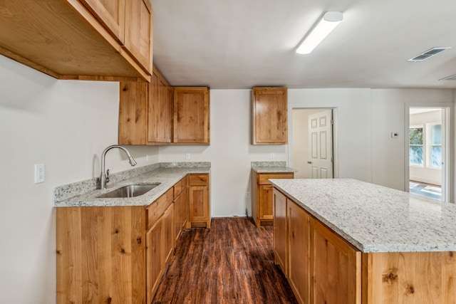 kitchen with a center island, dark hardwood / wood-style floors, sink, and light stone counters