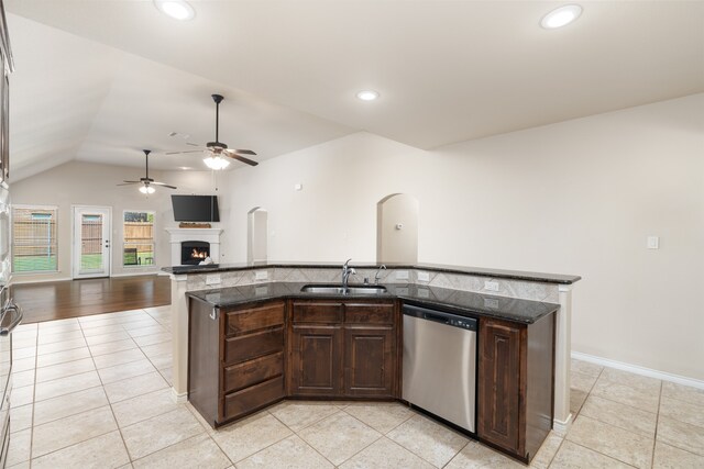 kitchen with dark brown cabinets, light tile patterned floors, vaulted ceiling, dishwasher, and sink