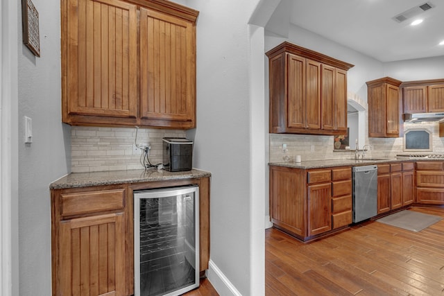 kitchen featuring dishwasher, backsplash, wine cooler, sink, and light wood-type flooring