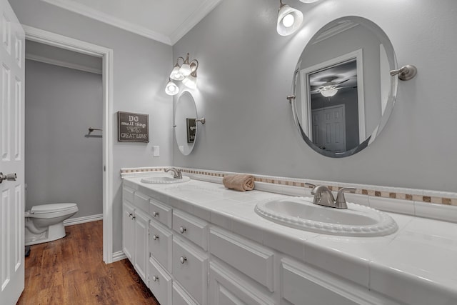 bathroom featuring vanity, crown molding, wood-type flooring, and toilet