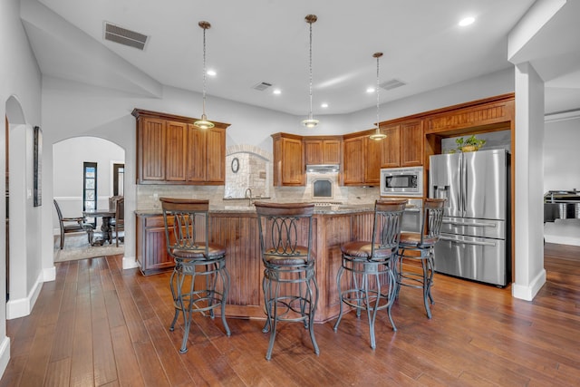 kitchen with light stone countertops, dark wood-type flooring, appliances with stainless steel finishes, and pendant lighting