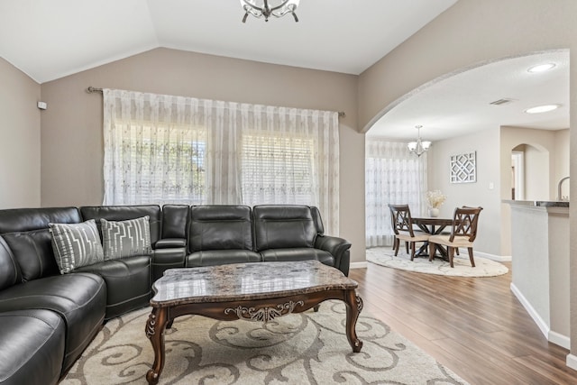 living room with lofted ceiling, a notable chandelier, and wood-type flooring