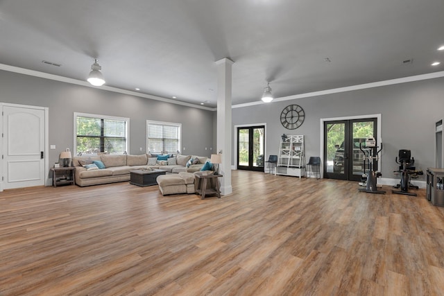 living room with ornamental molding, french doors, and light wood-type flooring