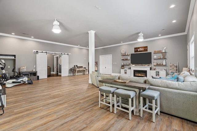 living room featuring light hardwood / wood-style floors, ornamental molding, and a barn door