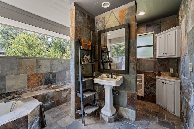 bathroom featuring tiled bath, tile walls, and sink