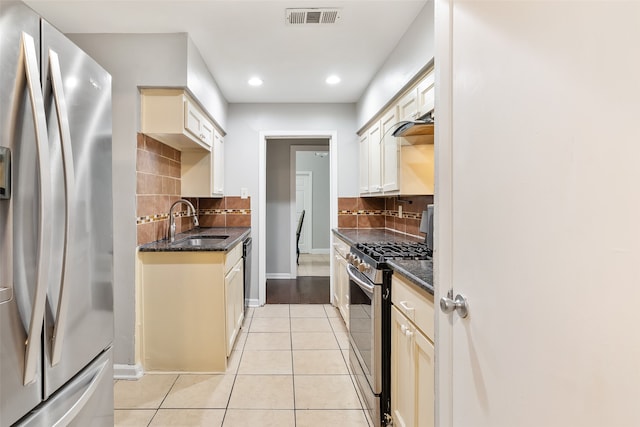 kitchen with sink, cream cabinetry, light tile patterned flooring, stainless steel appliances, and decorative backsplash