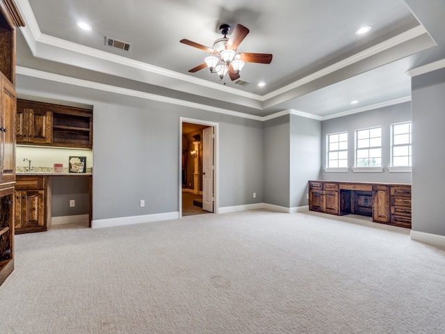 unfurnished living room featuring ceiling fan, light colored carpet, and a raised ceiling