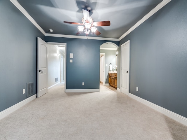 unfurnished bedroom with ornamental molding, ensuite bathroom, light colored carpet, and ceiling fan