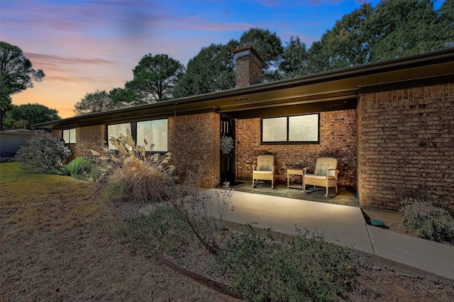 back house at dusk featuring a patio area