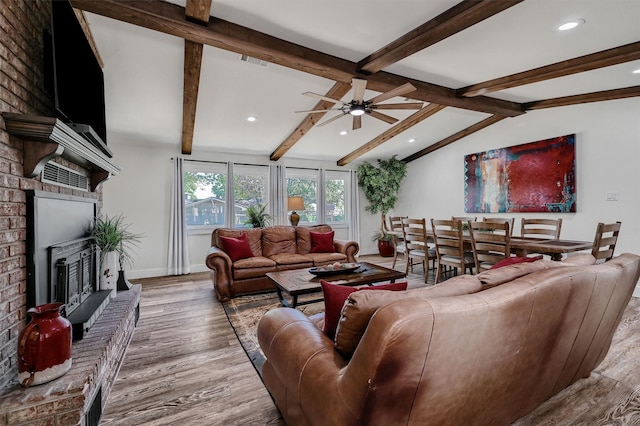 living room with hardwood / wood-style floors, lofted ceiling with beams, ceiling fan, and a brick fireplace