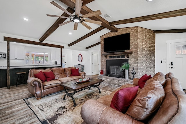 living room featuring light hardwood / wood-style floors, lofted ceiling with beams, a fireplace, and ceiling fan