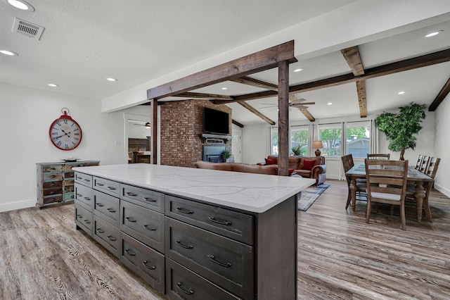 kitchen featuring light hardwood / wood-style flooring, lofted ceiling with beams, a brick fireplace, and ceiling fan