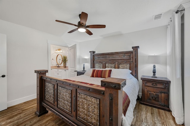 bedroom featuring dark hardwood / wood-style flooring, ensuite bath, and ceiling fan