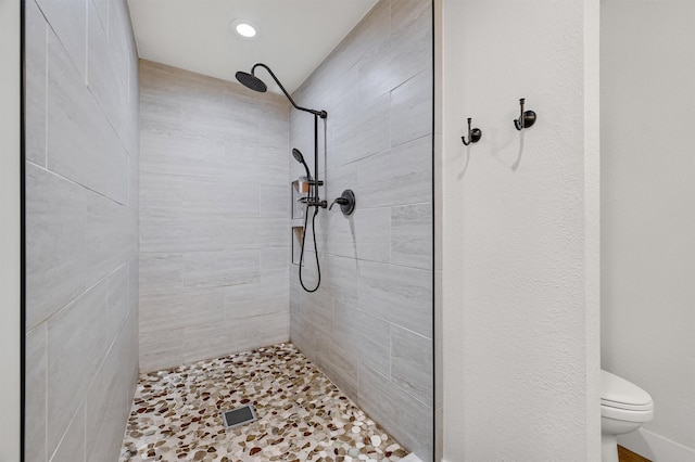 bathroom featuring a tile shower and toilet