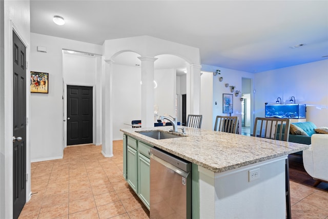 kitchen featuring a kitchen island with sink, ornate columns, sink, green cabinetry, and stainless steel dishwasher