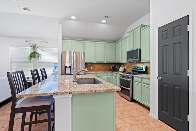 kitchen featuring a kitchen island with sink, stainless steel appliances, sink, vaulted ceiling, and green cabinetry