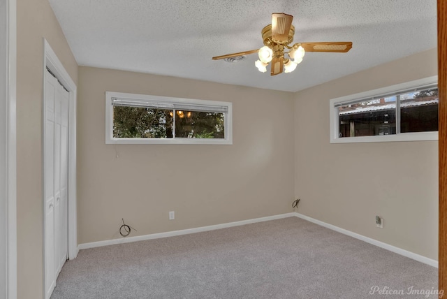 unfurnished bedroom with a closet, a textured ceiling, light colored carpet, and ceiling fan