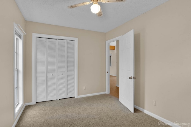 unfurnished bedroom with light carpet, a textured ceiling, a closet, and ceiling fan