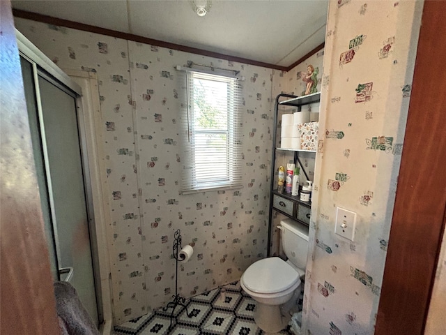 bathroom with a shower with door, crown molding, and toilet