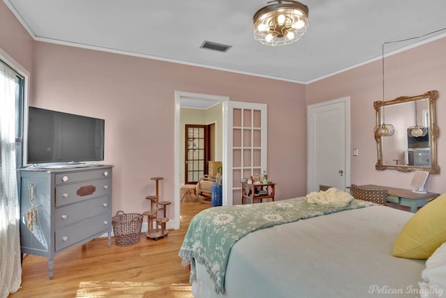 bedroom featuring ornamental molding, visible vents, and light wood-style flooring