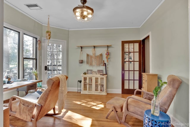 sitting room featuring ornamental molding, light wood-style flooring, visible vents, and baseboards