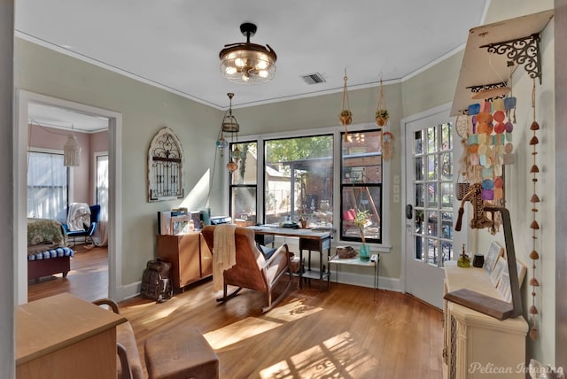 living area with light wood-style floors, plenty of natural light, and ornamental molding