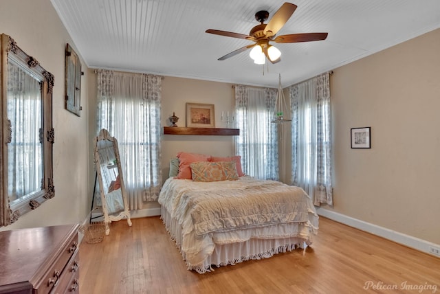 bedroom featuring multiple windows, ornamental molding, light wood-type flooring, and ceiling fan