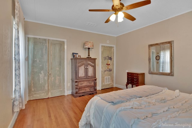 bedroom with baseboards, light wood-style flooring, visible vents, and crown molding