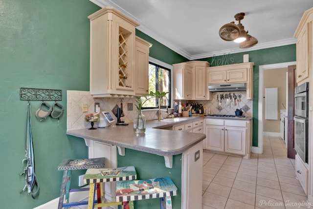 kitchen featuring cream cabinets, a kitchen bar, backsplash, kitchen peninsula, and crown molding