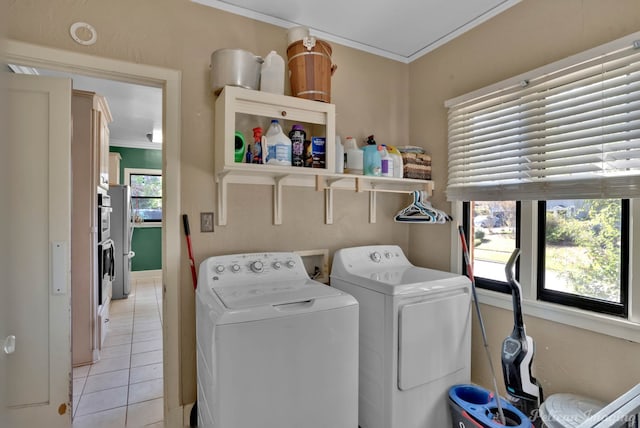 washroom featuring laundry area, light tile patterned flooring, ornamental molding, and washing machine and clothes dryer