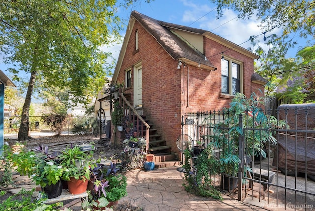 rear view of property with a patio area, stairs, fence, and brick siding