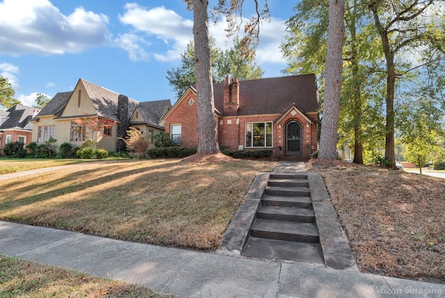 tudor-style house with brick siding and a front lawn