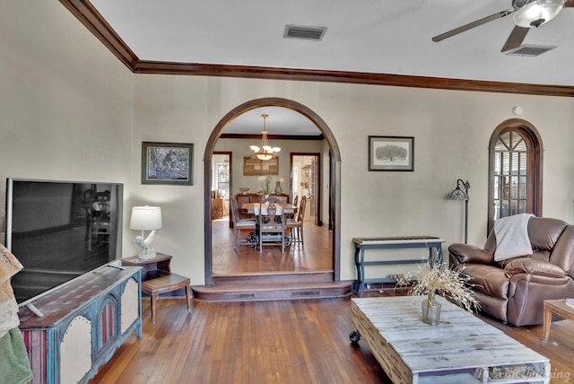 living room with arched walkways, crown molding, wood-type flooring, visible vents, and ceiling fan with notable chandelier