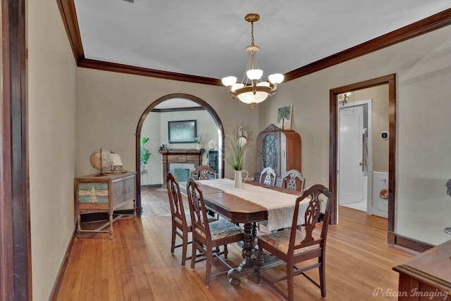 dining area featuring a notable chandelier, ornamental molding, and light hardwood / wood-style flooring