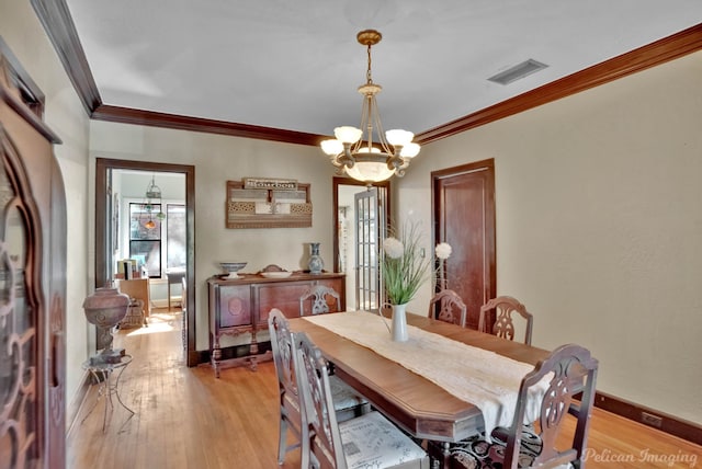 dining room featuring ornamental molding, light hardwood / wood-style flooring, and a chandelier