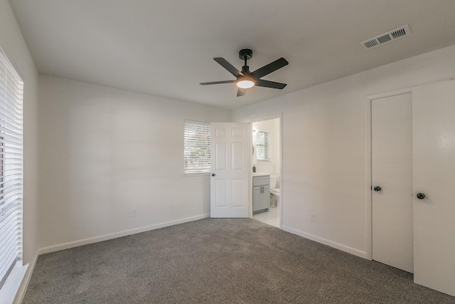 unfurnished bedroom with ceiling fan, light colored carpet, ensuite bathroom, and a closet