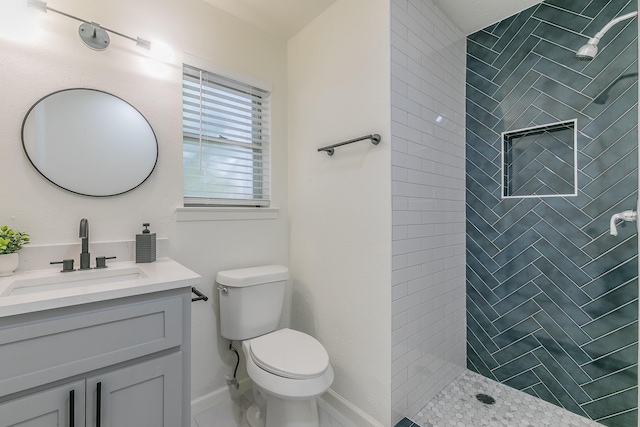 bathroom featuring vanity, toilet, and tiled shower