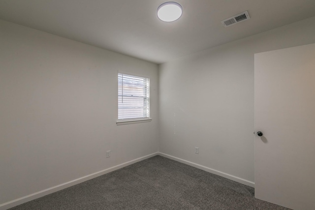 spare room with dark colored carpet