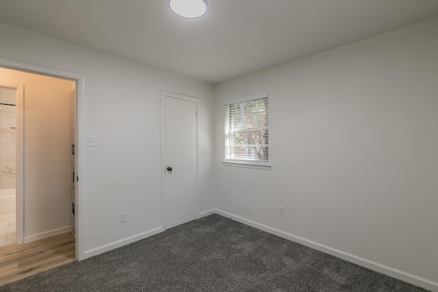 unfurnished bedroom with dark colored carpet and a closet