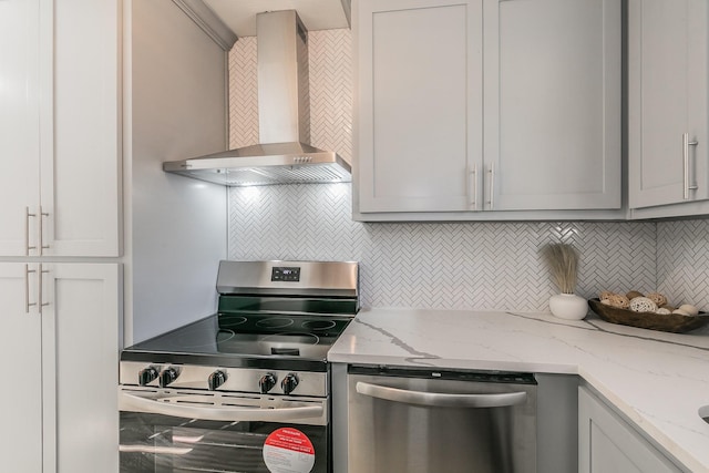 kitchen with light stone countertops, appliances with stainless steel finishes, tasteful backsplash, wall chimney exhaust hood, and gray cabinets