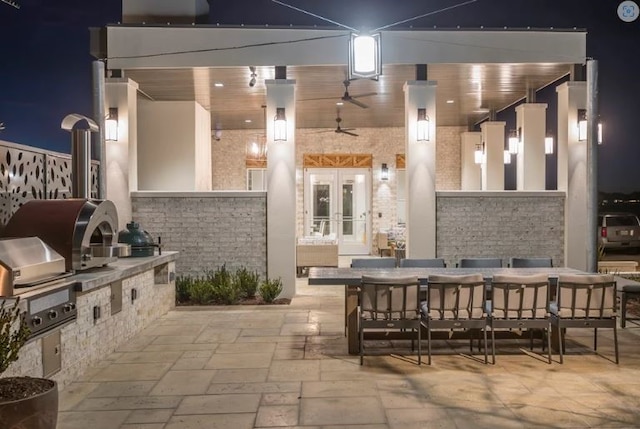 patio at night with an outdoor kitchen, french doors, and grilling area