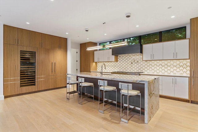 kitchen with pendant lighting, white cabinetry, custom range hood, and a large island