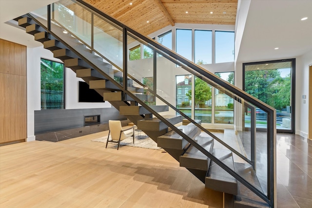 stairway with beam ceiling, high vaulted ceiling, wooden ceiling, and wood-type flooring