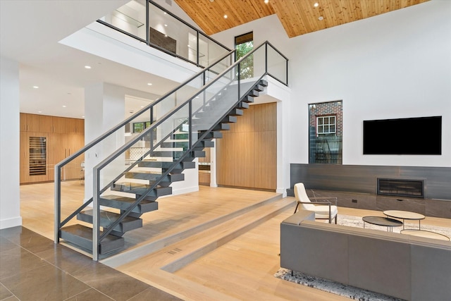 stairway with wooden walls, tile patterned flooring, wooden ceiling, and a high ceiling