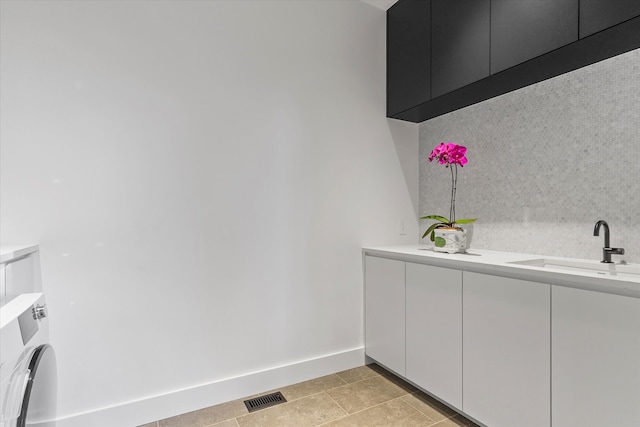 laundry area with light tile patterned flooring, cabinets, and sink