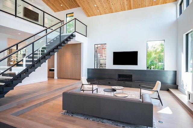 living room featuring a healthy amount of sunlight, light hardwood / wood-style floors, high vaulted ceiling, and wooden ceiling