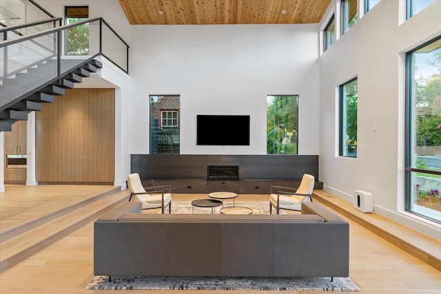 living room featuring a towering ceiling, wooden ceiling, and light hardwood / wood-style floors