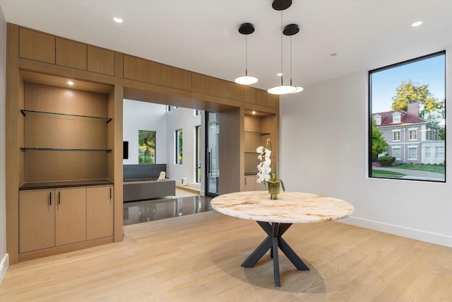 dining space with built in shelves and light hardwood / wood-style floors