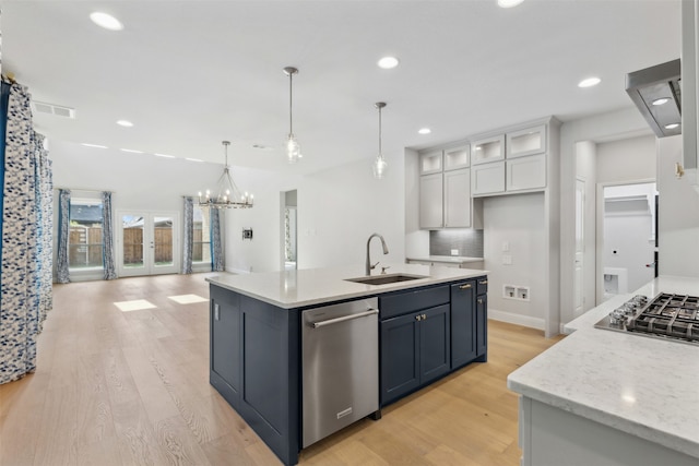 kitchen with appliances with stainless steel finishes, sink, hanging light fixtures, white cabinets, and light hardwood / wood-style flooring